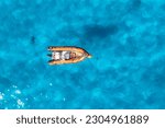 Aerial view of beautiful orange boat in blue sea at sunset in summer. Sardinia, Italy. Top drone view of motorboat, ocean with transparent azure water. Travel. Tropical landscape. Yachting. Seascape