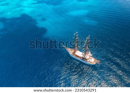 Aerial view of beautiful sailboat in blue sea at sunset in summer. Sardinia, Italy. Top drone view of yacht, ocean with transparent azure water. Travel. Tropical landscape. Yachting. Seascape. Boat