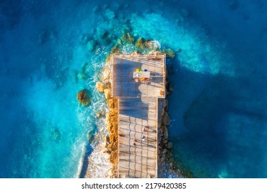 Aerial view of beautiful wooden pier, sea bay, sandy beach at sunset in summer. Top view of jetty, transparent blue water with waves, stones in lagoon, people. Tropical landscape. Vacation in Turkey - Powered by Shutterstock