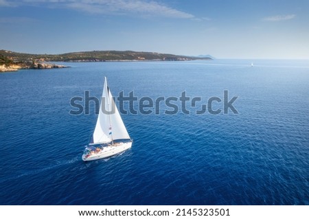 Aerial view of beautiful yacht. Boat on the sea at sunset in summer. Lefkada island, Greece. Top view of luxury yachts, sailboats, clear blue water, sky, mountain. Travel. Cruise vacation. Yachting