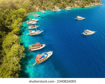 Aerial view of beautiful yachts and boats on the sea bay at sunset in summer. Fethiye lagoons, Turkey. Top view of luxury yachts, sailboats, clear blue water, sand, stones and green trees. Tropical - Powered by Shutterstock