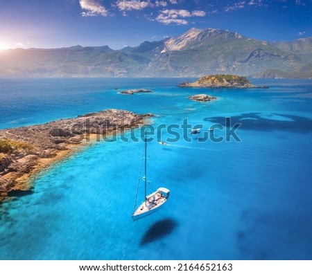 Aerial view of beautiful yachts and boats on the sea at sunset in summer. Akvaryum koyu in Turkey. Top view of luxury yachts, sailboats, clear blue water, rocky coast, sky, mountain. Travel. Scenery
