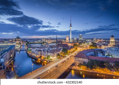 Aerial view of Berlin skyline with famous TV tower and Spree river in twilight during blue hour at dusk with dramatic clouds, Germany
