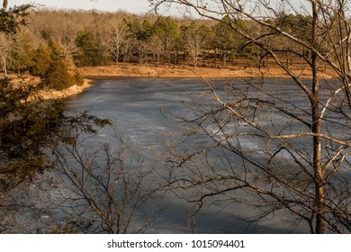 Aerial view from between trees looking at a frozen lake