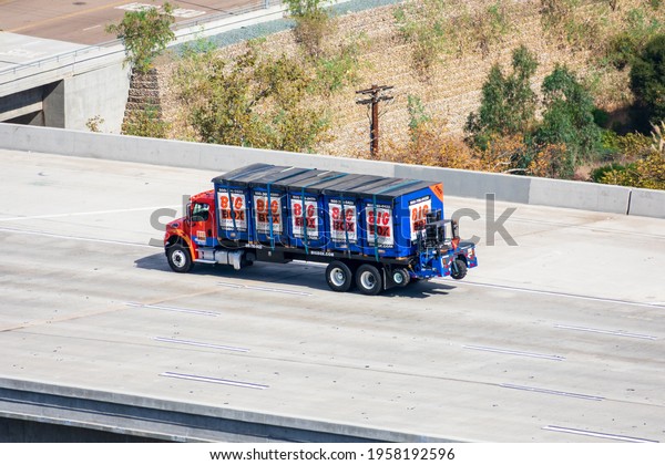 Aerial view of Big Box Storage delivery truck loaded\
with portable storage containers and driving on highway. - San\
Diego, California, USA -\
2020