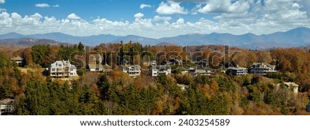 Aerial view of big family houses on mountain top between yellow trees in North Carolina suburban area in fall season. Real estate development in american suburbs