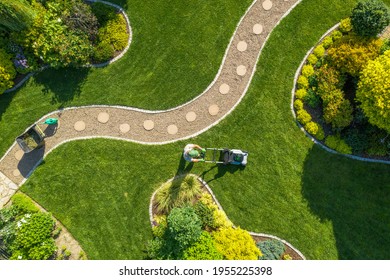 Aerial View Of Big Garden Grass Field Mowing By Caucasian Gardener. Summer Time Landscape Maintenance.