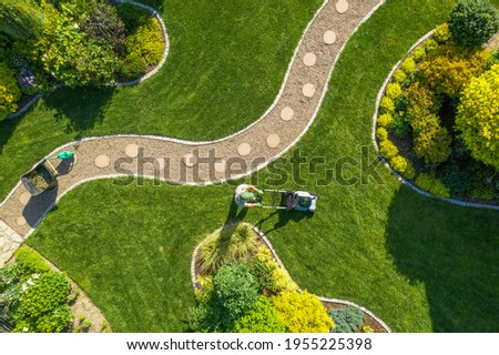 Aerial View of Big Garden Grass Field Mowing by Caucasian Gardener. Summer Time Landscape Maintenance.