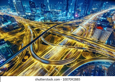 Aerial view of big highway interchange with traffic in Dubai, UAE, at night. Scenic cityscape. Colorful transportation, communications and driving background. - Shutterstock ID 1007092885