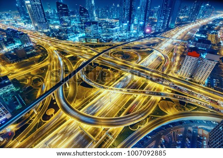 Aerial view of big highway interchange with traffic in Dubai, UAE, at night. Scenic cityscape. Colorful transportation, communications and driving background.