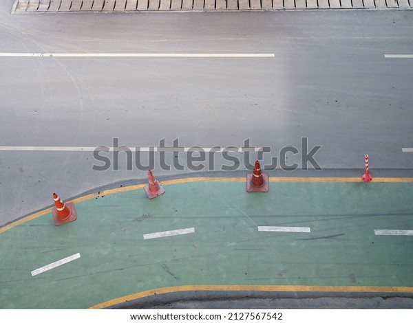 aerial view of bike\
lane, green asphalt road curves with traffic cones and dividing\
line, biking path way roadside for eco friendly traveling in city\
streets of Bangkok,\
Thailand