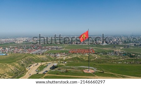 Aerial view of Bishkek city from the mountains. Flagpole with Kyrgyzstan flag