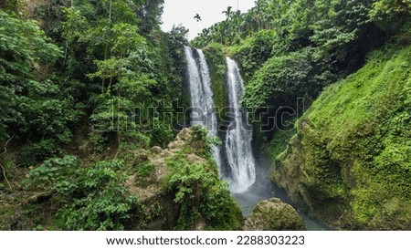 Aerial view of Blang Kolam waterfall with green and leafy trees in Aceh province, Indonesia