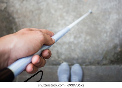 Aerial View of Blind Person Holding a Long White Cane; Demonstrating How to Measure Height of Curb with a Cane