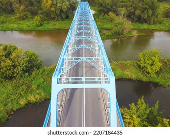 Aerial View Of A Blue Bridge Over A Lazy River In Green Scenery