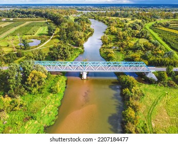 Aerial View Of A Blue Bridge Over A Lazy River In Green Scenery