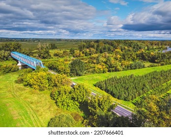 Aerial View Of A Blue Bridge Over A Lazy River In Green Scenery