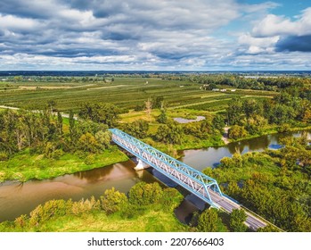 Aerial View Of A Blue Bridge Over A Lazy River In Green Scenery