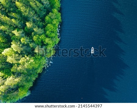 Aerial view of blue lake with fishing boat and green woods in summer Finland
