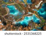 Aerial view of blue lakes in red autumn forest at sunrise. Morning in Plitvice Lakes park, Croatia. Colorful landscape with azure water, trees, wooden trails and bridges, orange foliage. Top view