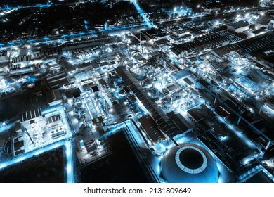 Aerial View Of Blue Light Industrial Factory With Chemical Refinery And Building Material Glowing Light At Night