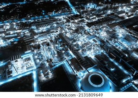 Aerial view of blue light industrial factory with chemical refinery and building material glowing light at night