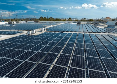 Aerial view of blue photovoltaic solar panels mounted on industrial building roof for producing clean ecological electricity. Production of renewable energy concept