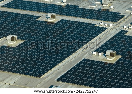 Aerial view of blue photovoltaic solar panels mounted on industrial building roof for producing green ecological electricity. Production of sustainable energy concept