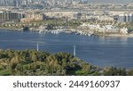 Aerial view of blue river near green park with luxury yachts at sunny day with blue sky Timelapse in Dubai Creek, Dubai, United Arab Emirates