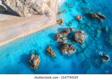 Aerial view of blue sea, rocks in clear water, white sandy beach at sunset in summer. Porto Katsiki, Lefkada island, Greece. Beautiful landscape with sea coast, stones in azure water, waves. Top view - Shutterstock ID 2147745529