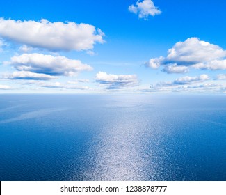 Aerial View Of A Blue Sea Water Background And Sun Reflections. Aerial Flying Drone View. Waves Water Surface Texture On Sunny Tropical Ocean. Aerial Photography. Birdseye. Sea, Beach, Sky, Clouds.