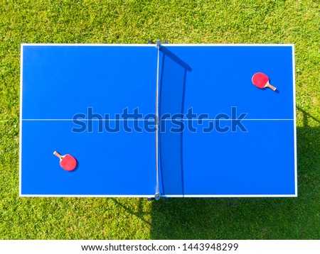Aerial view blue table tennis or ping pong. Close-up ping-pong net. Close up ping pong net and line. Top view two table tennis or ping pong rackets or paddles  and ball on a blue table with net