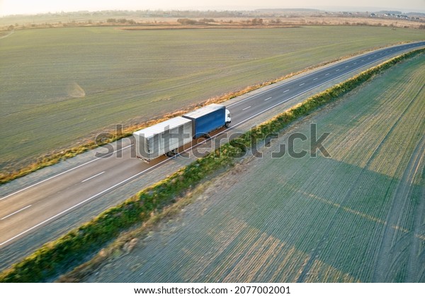 Aerial view of blurred fast moving\
semi-truck with cargo trailer driving on highway hauling goods in\
evening. Delivery transportation and logistics\
concept.