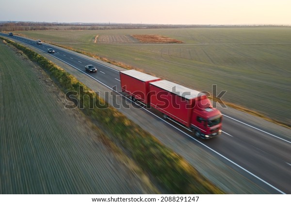 Aerial view of blurred fast moving\
semi-truck with cargo trailer driving on highway hauling goods in\
evening. Delivery transportation and logistics\
concept