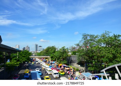 Aerial View Blurred Vehicle On Street And Thai People And Foreign Travelers Walking Waiting At Bus Station With Landscape Of Traffic Jatujak Road And Cityscape Of Chatuchak City In Bangkok, Thailand