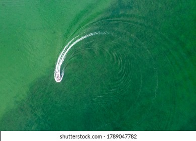 Aerial view of boat doing circles in green lake water