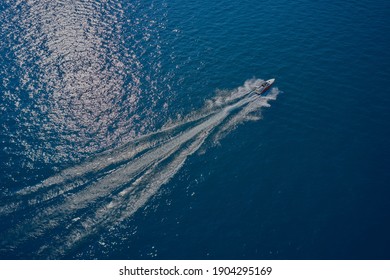  Aerial view of a boat in motion on blue water. Top view of a white boat sailing in the blue sea. luxury motor boat. Drone view of a boat sailing at high speed.