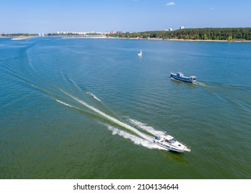 Aerial View Of The Boat Rushing Towards The Ship On A Wide River Near The Forest On A Sunny Summer Day