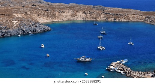 Aerial view of boats anchored in a calm bay with clear blue water and rocky coastline in Lindos, Rhodes, Greece. - Powered by Shutterstock