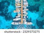 Aerial view of boats and luxure yachts in dock at sunset in summer in Sardinia, Italy. Colorful landscape with sailboats and motorboats in sea bay, jatty, clear blue sea. Top view of harbor. Travel