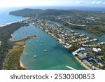 Aerial view of boats on the Noosa River, buildings in Noosaville and Noosa Heads, and Noosa National Park in Queensland, Australia