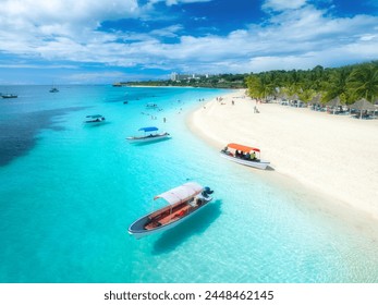 Aerial view of the boats on tropical sea coast with white sandy beach at sunset. Summer vacation in Kendwa, Zanzibar. Landscape with boat, yacht, clear water, green palms, blue sky. Top drone view - Powered by Shutterstock