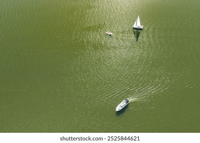 Aerial view of boats sailing on a calm green lake, showcasing a tranquil summer scene. Ideal for nature enthusiasts and travel promotions. - Powered by Shutterstock