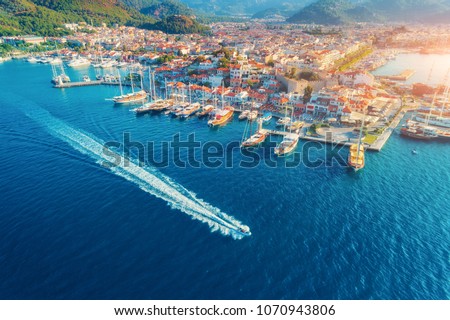Aerial view of boats, yahts, floating ship and beautiful architecture at sunset in Marmaris, Turkey. Landscape with boats in marina bay, blue sea, city. Top view of harbor with yacht and sailboat.