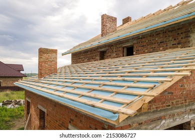 Aerial view of a brick house with wooden roof frame under construction. - Shutterstock ID 2153086727