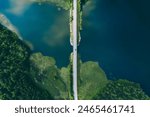 Aerial view of bridge asphalt road with cars and blue water lake and green woods. Beautiful summer landscape in Finland.