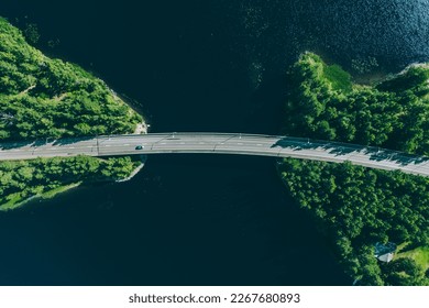 Aerial view of bridge road through blue lakes with green woods in summer Finland.