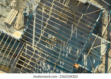 Aerial view of builders working on unfinished residential house with wooden roof frame structure under construction in Florida suburban area - Shutterstock ID 2362104323