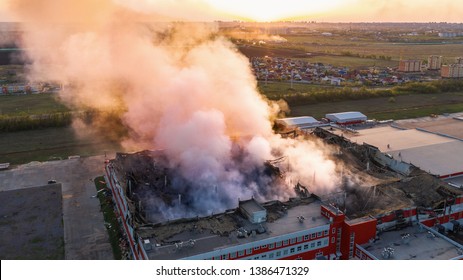 Aerial View Of Burnt Industrial Warehouse Or Logistics Center Building After Big Fire With Huge Smoke From Burned Roof, Drone Shot