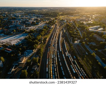 Aerial View of Bustling Train Yard Adjacent to a Picturesque Urban Landscape at Sunset - Powered by Shutterstock